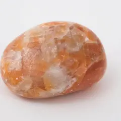 En polerad sten av orange kalcit med sina unika egenskaper, som skimrar i ljuset.