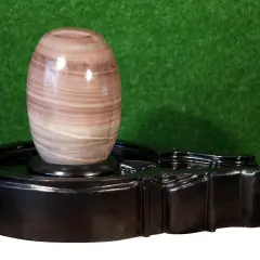 En vackert randig shiva linga av sten vilar på ett svart, glänsande altare.