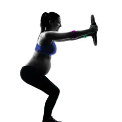 Gravid kvinna tränar pilates med en ring.