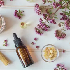 En lugnande scen med aromaterapi oljor, tända ljus, örter och blommor.