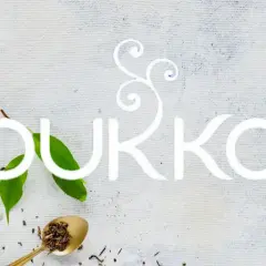 En kopp te med en tepåse, teblad och sockerbitar. Texten "PUKKA" i vitt. En sann pukka love för teälskare.