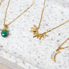 Fyra guldfärgade halsband med olika hängen: en stjärna, en grön sten, en sol och en måne. Vilken kristall passar mig?