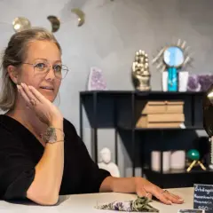 Kvinna med glasögon i butik med kristaller. Hon pratar om apatit betydelse, kanske om dess helande krafter.