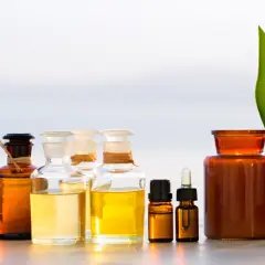 Flera flaskor med ekologisk massageolja och en grönskande blad.