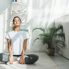 Kvinna i ashtanga yoga position på en matta, med slutna ögon och ett leende.