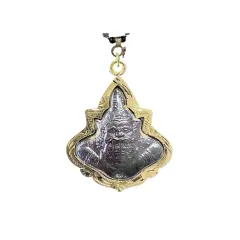 Ett detaljerat buddha halsband med en ansiktsliknande amulett i en guldfärgad ram.