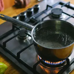 En kastrull med koksalt vatten bubblar på spisen. En grön paprika ligger bredvid.
