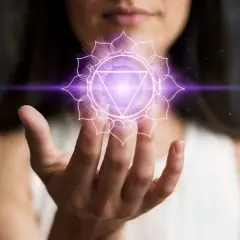 En kvinna håller upp sin hand där ett lysande lila kronchakra svävar.