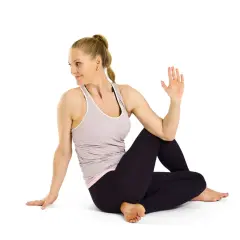 Kvinna utför Ardha Matsyendrasana, en sittande vridning som stärker ryggen och magen.