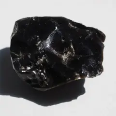 En bit glänsande, svart obsidian svenska, med en skugga som faller åt vänster.