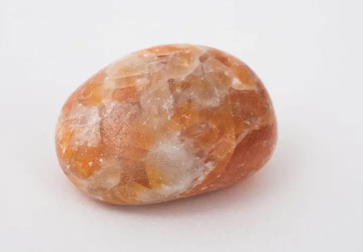 En polerad sten av orange kalcit med sina unika egenskaper, som skimrar i ljuset.