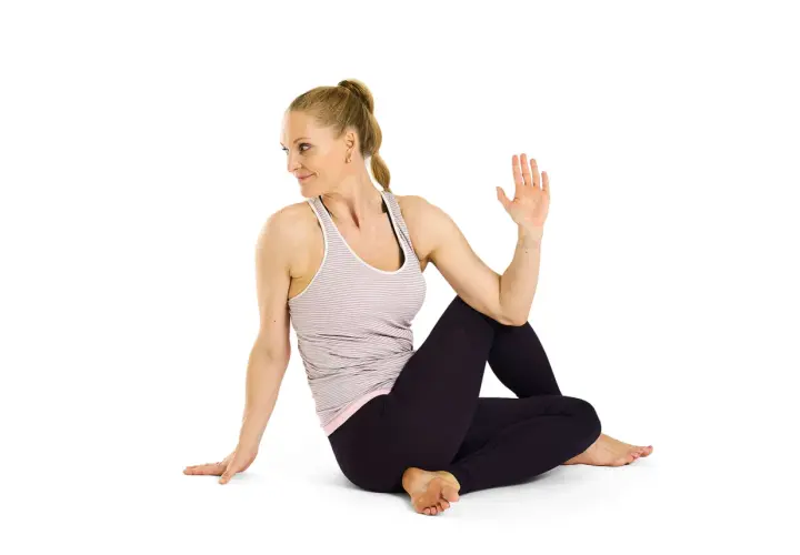 Kvinna utför Ardha Matsyendrasana, en sittande vridning som stärker ryggen och magen.
