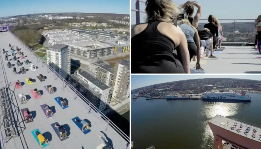 Grupp som utövar urban yoga på ett tak med utsikt över stad och hamn.
