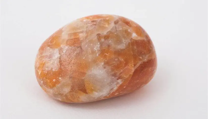 En polerad sten av orange kalcit med sina unika egenskaper, som skimrar i ljuset.