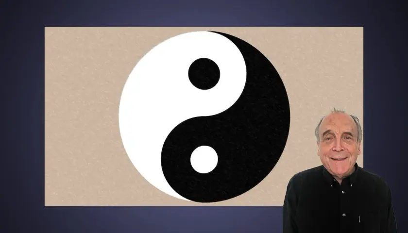 En man ler bredvid en yin och yang-symbol.