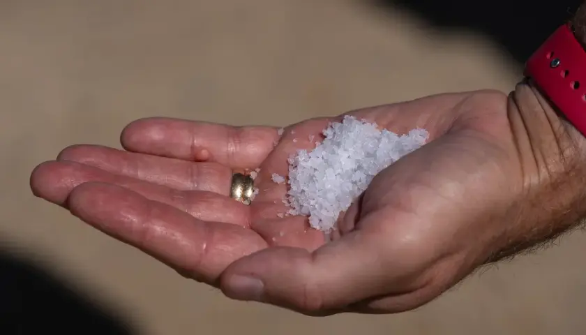 En hand håller en guldring och en hög med kristallsalt.