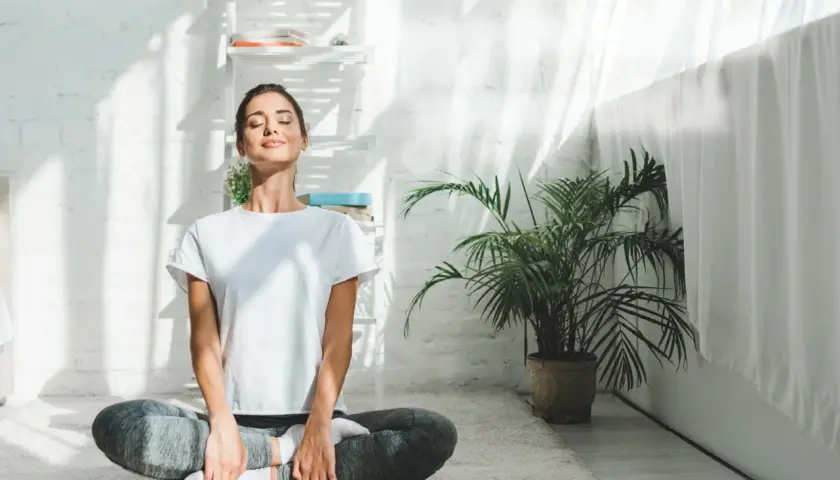 Kvinna i ashtanga yoga position på en matta, med slutna ögon och ett leende.