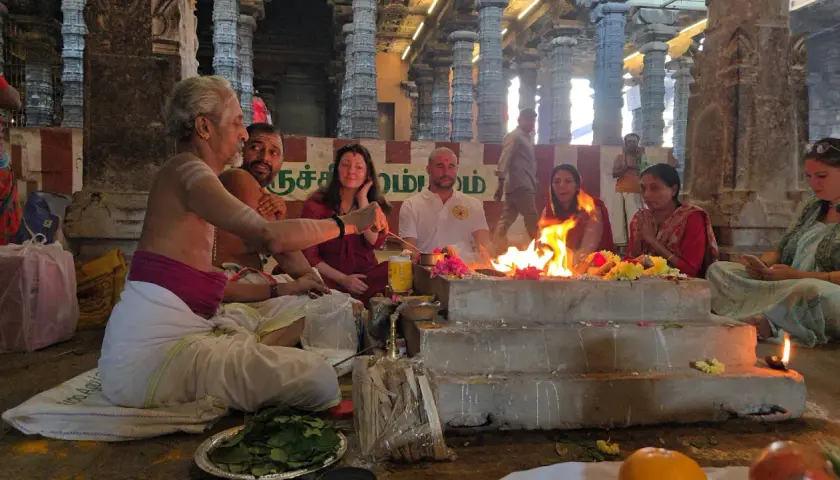 En präst leder en grupp människor i en eldceremoni, en form av puja. Vad betyder puja? Det är en hinduisk ritual för att visa vördnad.