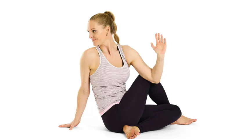 Kvinna utför Ardha Matsyendrasana, en sittande vridning som stärker ryggen och magen.