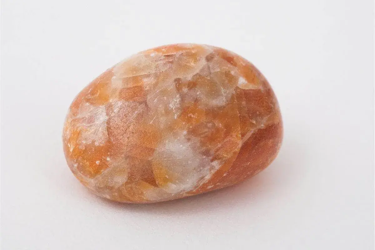 En polerad sten av orange kalcit med sina unika egenskaper, som skimrar i ljuset.