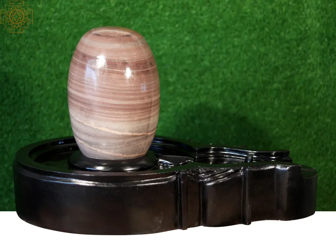 En vackert randig shiva linga av sten vilar på ett svart, glänsande altare.