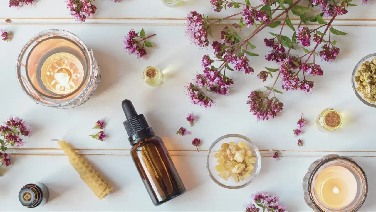 En lugnande scen med aromaterapi oljor, tända ljus, örter och blommor.