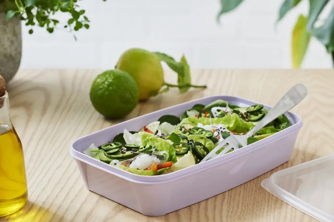 En fräsch sallad med gröna blad, jalapeños och avokado i en lila matlåda. Perfekt för **organisk mat** på språng.