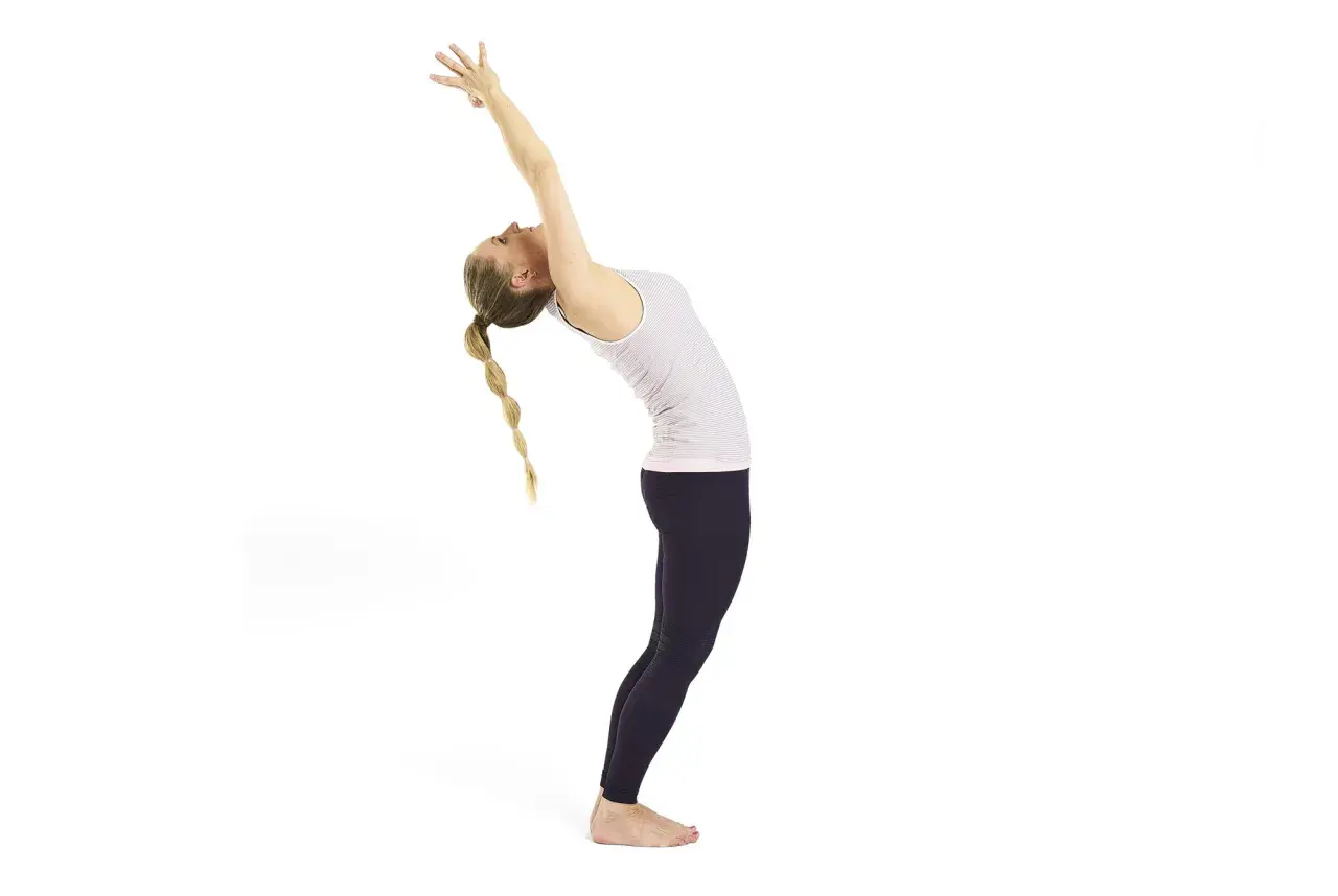 Kvinna i urdhva dhanurasana, en bakåtböjning med armarna sträckta uppåt. Hennes flätade hår faller bakåt.