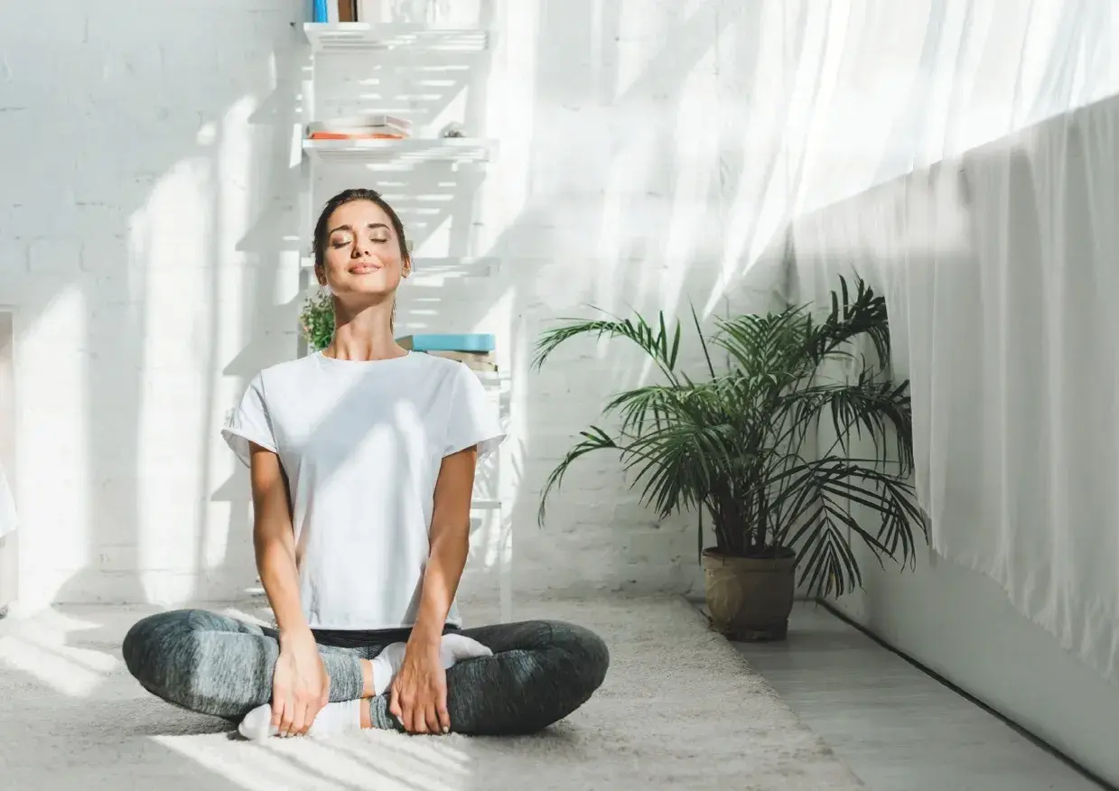 Kvinna i ashtanga yoga position på en matta, med slutna ögon och ett leende.