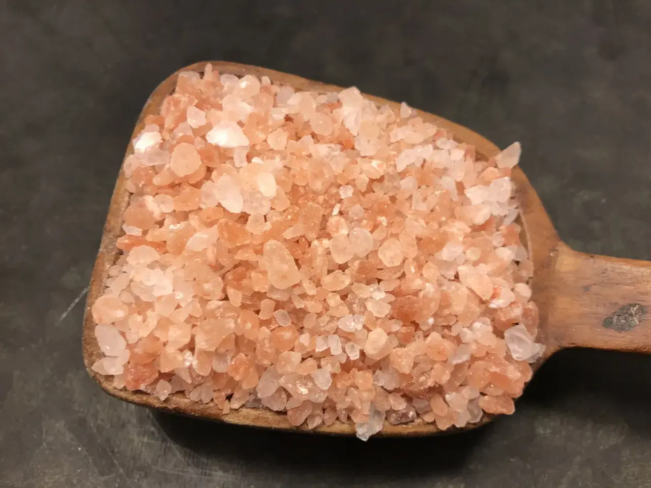 En träskopa fylld med rosa himalayasalt. Många anser att detta naturliga salt är nyttigt och ger en fin färg till maten.