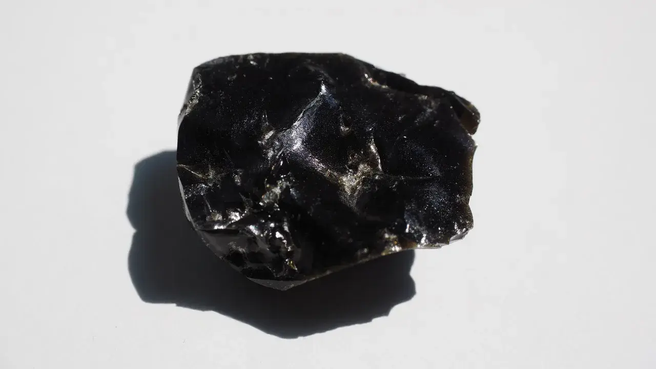 En bit glänsande, svart obsidian svenska, med en skugga som faller åt vänster.