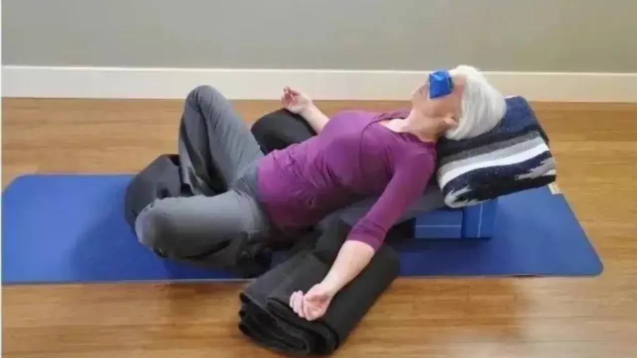 Kvinna i avslappnad supta baddha konasana med ögonmask och stöd.