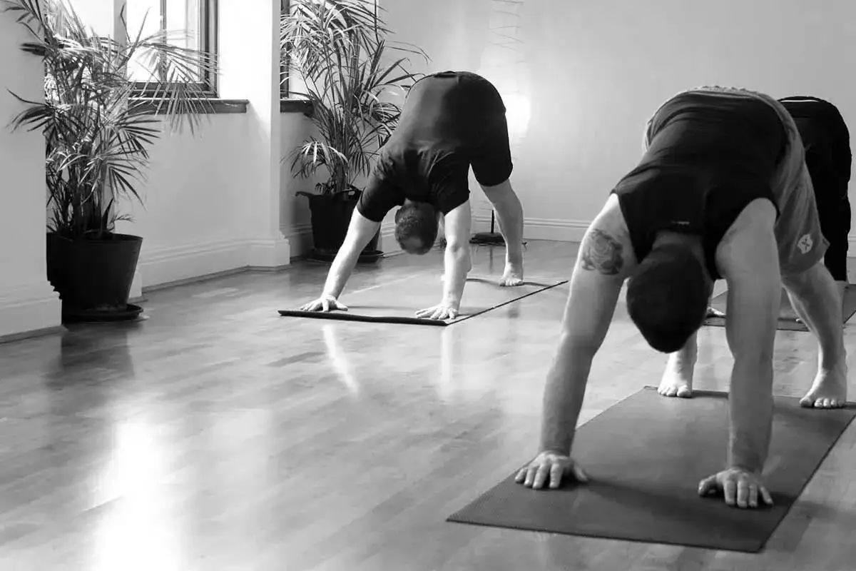 M&auml;n utf&ouml;r ashtanga yoga positioner i ett ljust rum med v&auml;xter.
