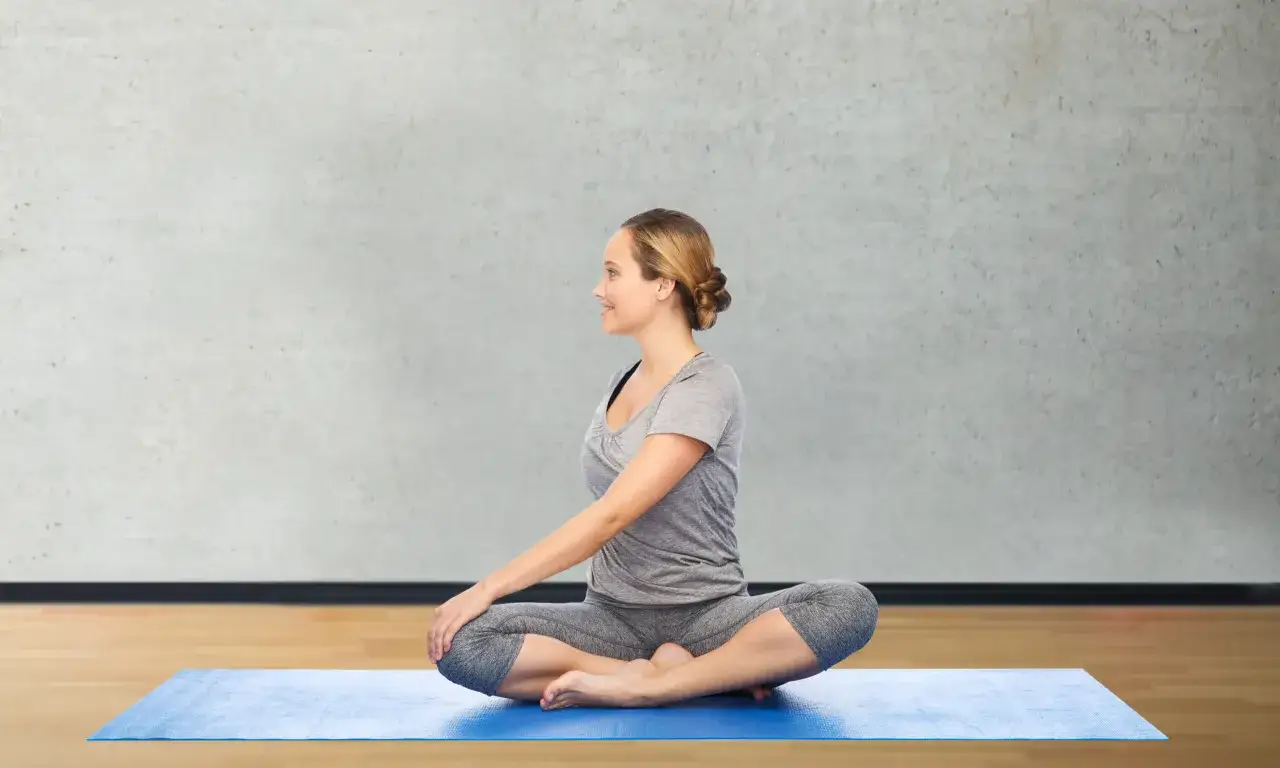 Kvinna i meditationsst&auml;llning p&aring; en bl&aring; matta, lugnar sin vagusnerv och minskar &aring;ngest.