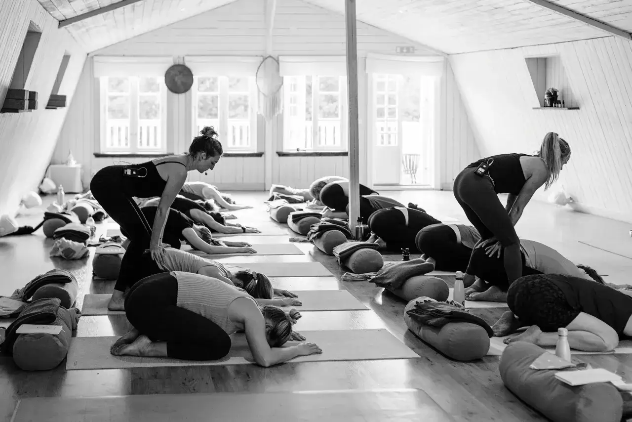 Grupp i barnets position under yoga. En instrukt&ouml;r guidar. Dr&ouml;mmer om en yoga utbildning csn.
